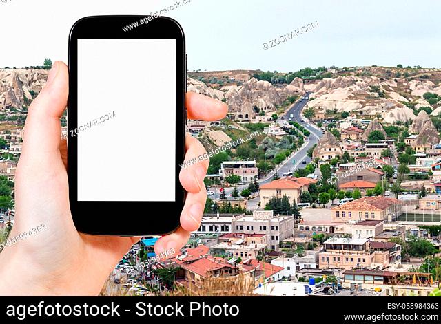 travel concept - tourist photographs of road in modern residential district in Goreme town in spring in Turkey on smartphone with empty cutout screen with blank...