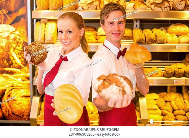 Bakers presenting loafs of bread in a bakery
