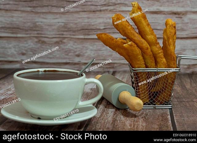 cup of hot chocolate with freshly made churros on wooden background typical spanish breakfast on holidays