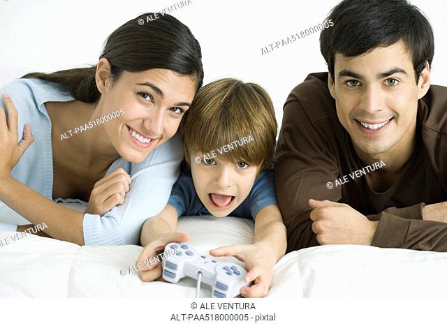 Little boy playing video game, parents watching