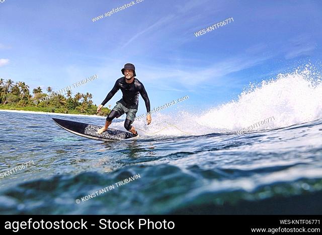 Man wearing hat surfing in sea on sunny day