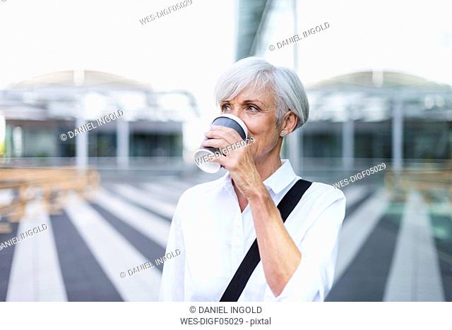 Senior businesswoman in the city drinking coffee
