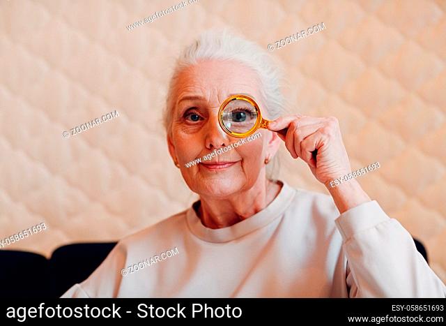 The elderly woman with magnifier loupe in hand
