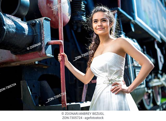 Portrait of happy wedding bride near the old steam locomotiv