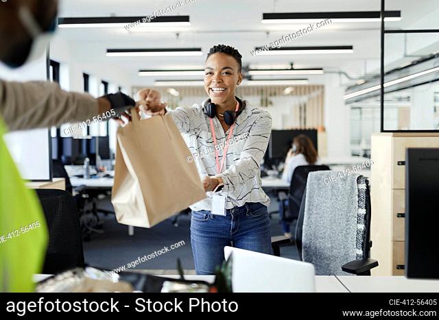 Happy businesswoman receiving lunch delivery from courier in office