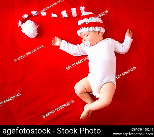 Little baby in knitted red whitey hat on red blanket