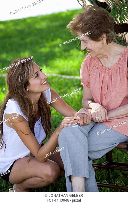 A senior woman and a young woman sitting together outside