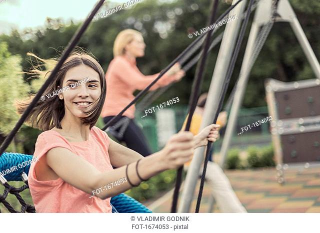 Smiling women swinging on swing at playground