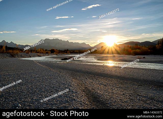 A sun star forms at sunset on the streambed of the Isar River near Wallgau in the Werdenfelser Land region of Bavaria near Wallgau