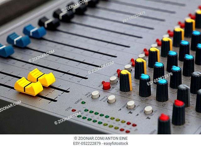 Close up audio control sound mixing console board with fader bars, buttons and sliders, high angle view