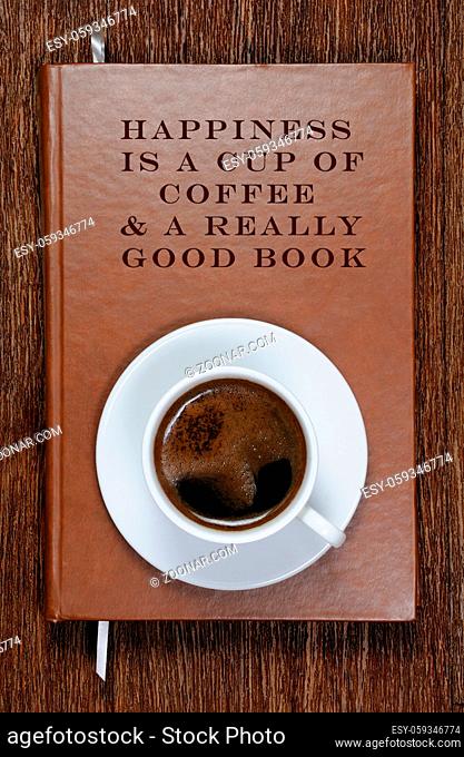 HAPPINESS IS A CUP OF COFFEE A REALLY GOOD BOOK . A book with a motivational quote and a cup of coffee