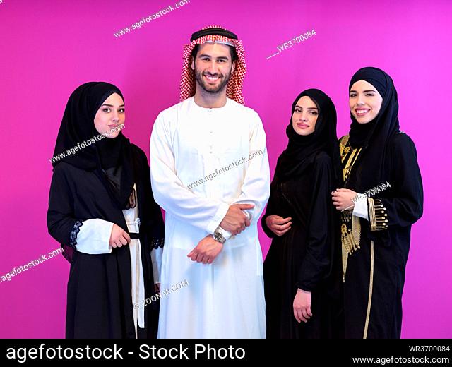group portrait of young muslim people arabian man with three muslim women in fashionable dress with hijab isolated on pink background representing modern islam...