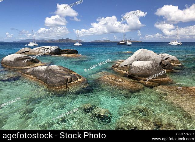 Boulders dot the waters of the Baths with boats moored in the distance at the Baths on Virgin Gorda in the British Virgin Islands