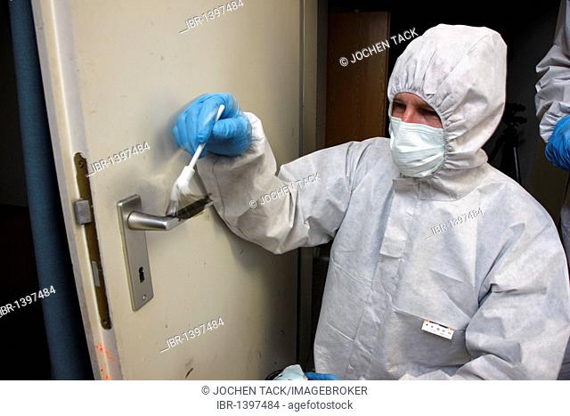 Fingerprints are being made visible with charcoal powder and secured on adhesive film, officer of the C.I.D., the Criminal Investigation Department