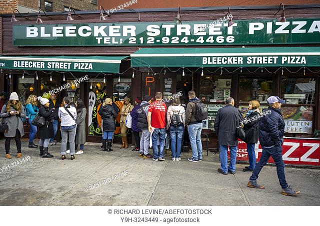 Hungry pizza lovers line up outside waiting to enter the popular Bleecker Street Pizza in the Greenwich Village neighborhood of New York on Friday, October 26