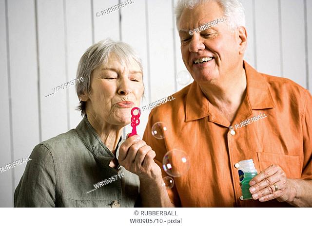 Close-up of an elderly couple blowing bubbles with a bubble wand