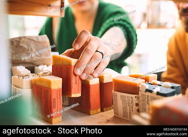 Woman picking up soap bar from rack in shop