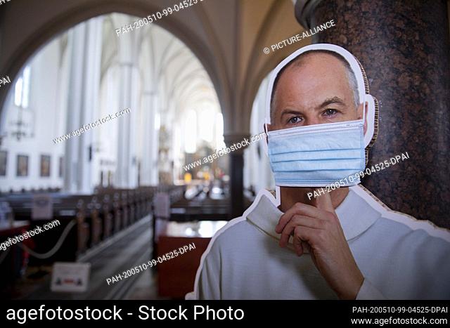 10 May 2020, Berlin: An erector of a clergyman with a mouth-and-nose protection, who commands silence, stands in front of a service in the entrance area of the...