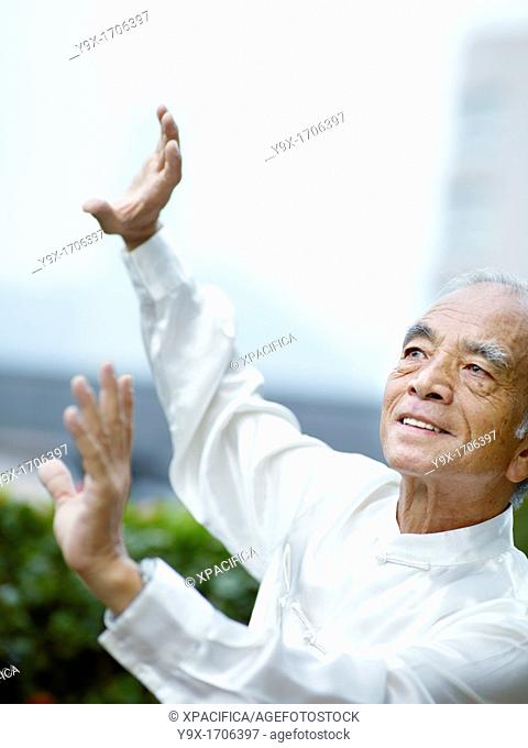 William Ng, a Tai Chi master practicing Tai Chi on the deck of The Peninsula Hotel, overlooking Hong Kong Victoria Harbour skyline