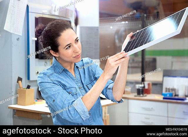 Businesswoman examining solar panel model in factory