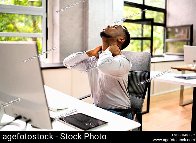 Employee Stretching At Office Desk At Work
