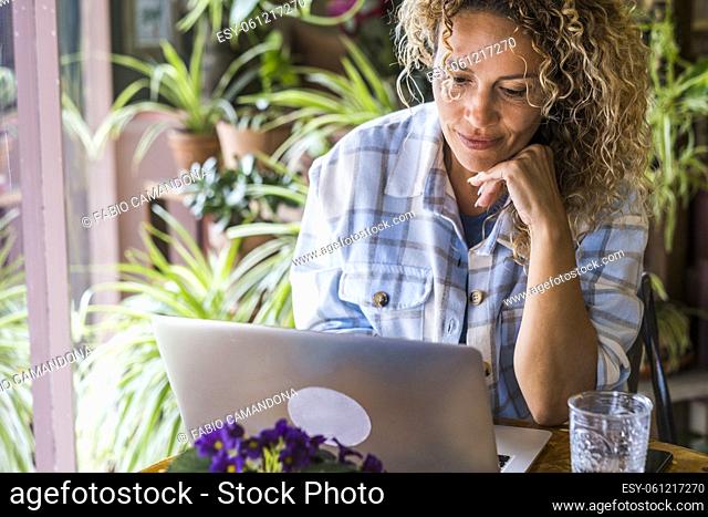Mature woman work at computer sitting on home office desktop and smiling looking the laptop - free modern freelance worker people - smart working online...