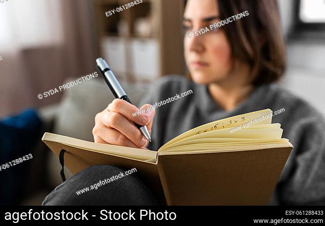 sad woman with diary sitting on sofa at home