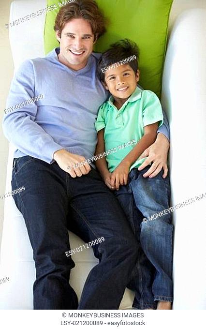 Overhead View Of Father And Son Relaxing On Sofa