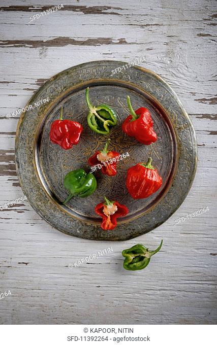 Scotch Bonnet chillis, whole and halved, on a metal plate
