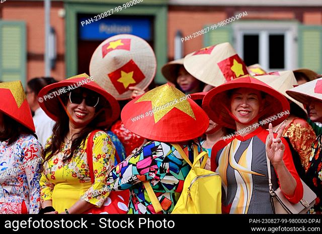 27 August 2023, Saxony-Anhalt, Wernigerode: Participants of a parade stand with Asian cone hats before the parade through the old town in Wernigerode