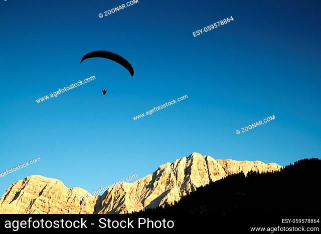 silhouette of paraglider in Dolomite mountain landscape in evening light near La Valle