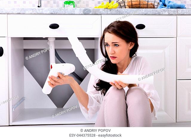 Upset Woman Looking At Damaged Sink Pipe