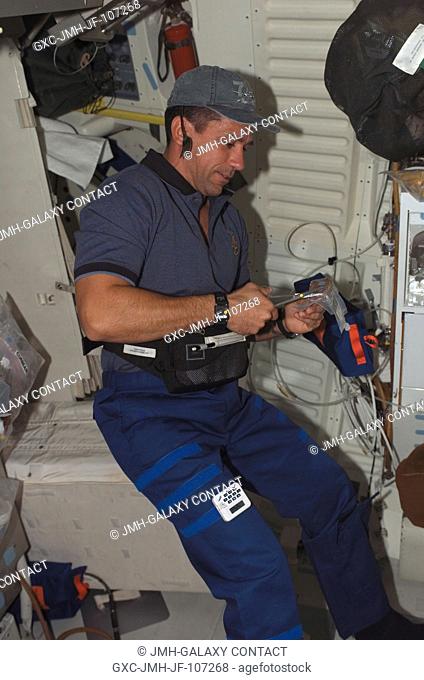 Astronaut William A. (Bill) Oefelein, STS-116 pilot, opens a package of food on the middeck of Space Shuttle Discovery
