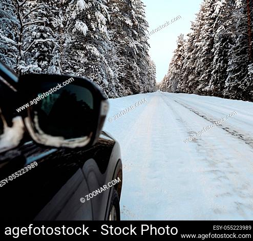 Passenger black car moving on winter road among deep forest
