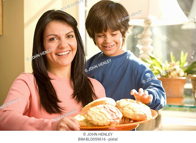Hispanic mother and son holding plate of cookies