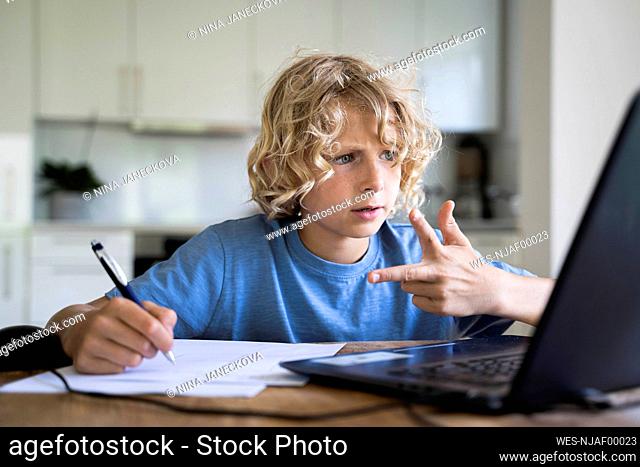 Boy counting through fingers looking at laptop