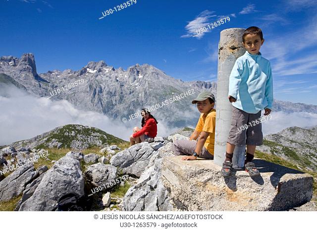 Family in the summit of Peña Maín next to a gedesic vertex, Urrieles massif, in the Picos de Europa National Park, Asturias, Spain