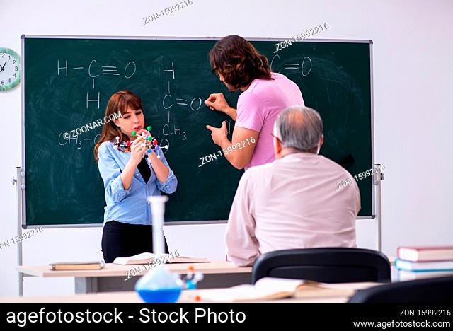 Old teacher and two students in the classroom