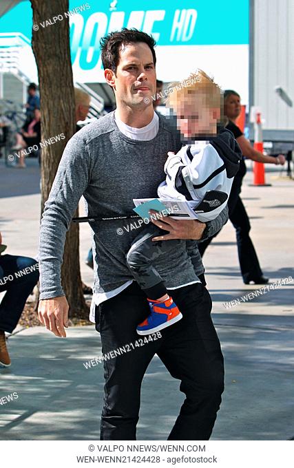 Mike Comrie carries his son Luca Comrie who holds a toy hockey stick to Game 1 of the Stanley Cup Finals between the Los Angeles Kings and New York Rangers...