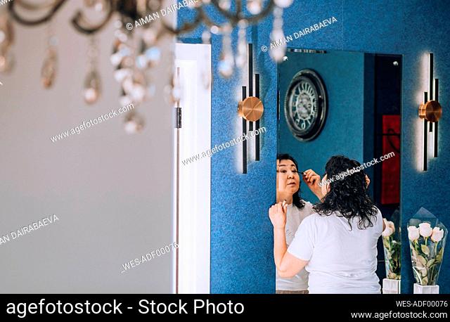 Woman getting dressed looking in mirror at home