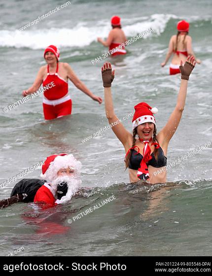 24 December 2020, Mecklenburg-Western Pomerania, Warnemünde: Decorated for Christmas, members of the Rostock Seal Club go swimming in the 6