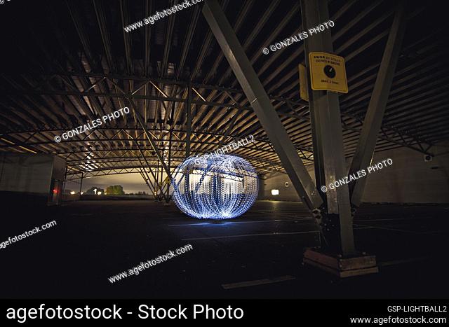 A creative person is creating a light ball in an industrial hall