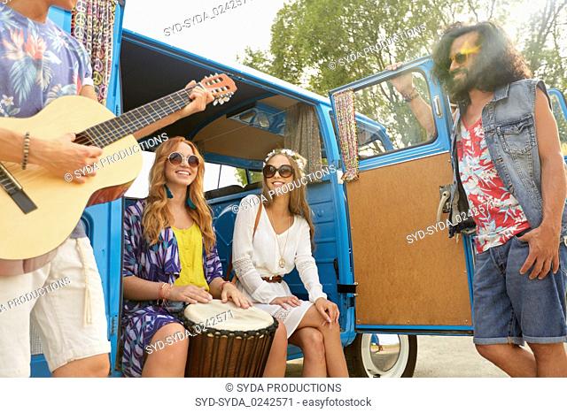 happy hippie friends playing music in minivan