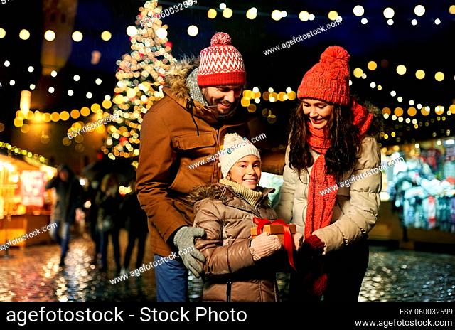 happy family with gift at christmas market in city