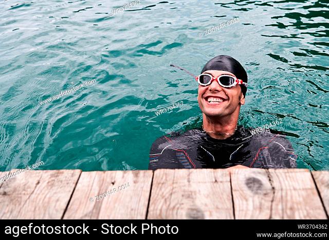 authentic triathlete swimmer portrait wearing wetsuit on morning training