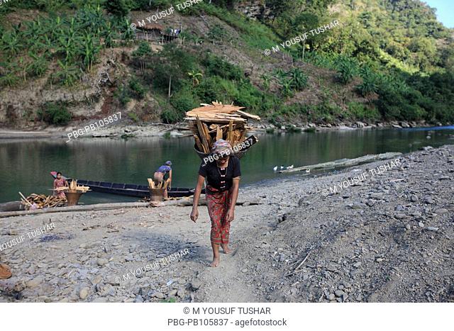 An ethnic Marma woman carries basket of firewood on her back at the bank of Sangu river Bandarban, Bangladesh December 2009