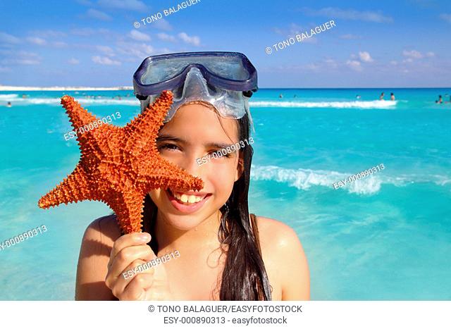 latin tourist girl holding starfish in tropical beach