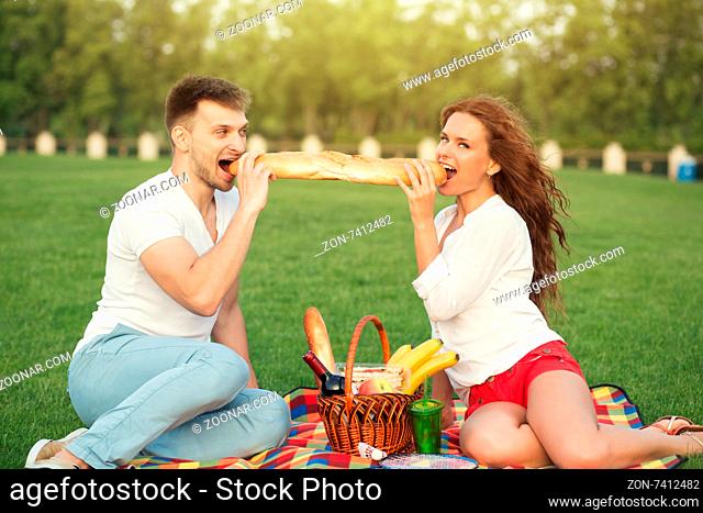Portrait of happy couple eating. Couple relaxing in the picnic and looking at photographer