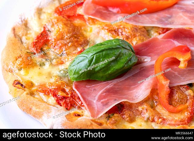 Detail einer Pizza mit Schinken und Basilikum