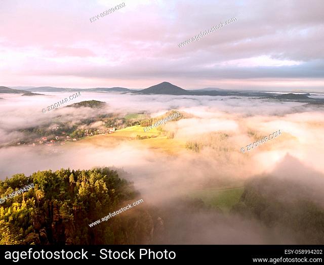 Spring misty landscape. Morning in beautiful hills of natural park. Rocky peaks increased from heavy creamy fog